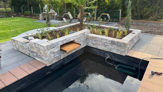 Moderner Gartenpool mit Natursteinmauer und Bepflanzung