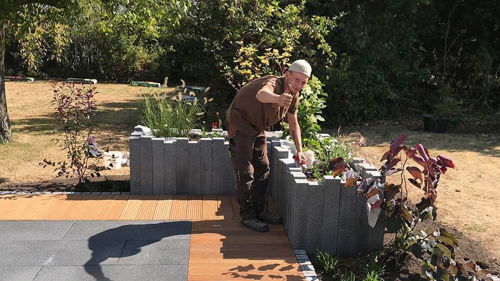 Mitarbeiter der Schatzgarten GmbH bei Gartenarbeiten zeigt Daumen hoch